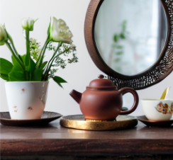 A generated photo realistic image of a teapot sitting on a table next to a mirror mounted on a wall