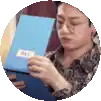 a man wearing glasses is holding a blue book in his hands .