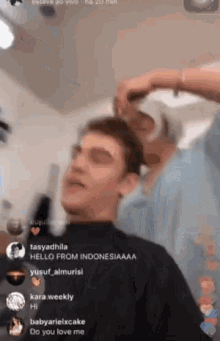 a man in a black shirt is getting his hair cut by a woman in a blue shirt