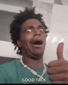 a man in a green shirt is giving a thumbs up and says good talk